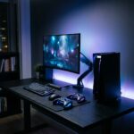 Console de videogame moderno em uma mesa com iluminacao azul e roxa de fundo.