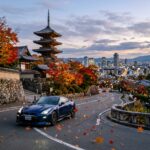 Um carro esportivo de alta performance em uma paisagem japonesa que mistura templos tradicionais e arranha-ceus modernos, com petalas de cerejeira caindo no outono.