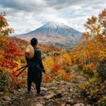 Guerreira Atsu olhando para o Monte Yotei com folhas vermelhas de outono ao redor, estilo fotografia editorial